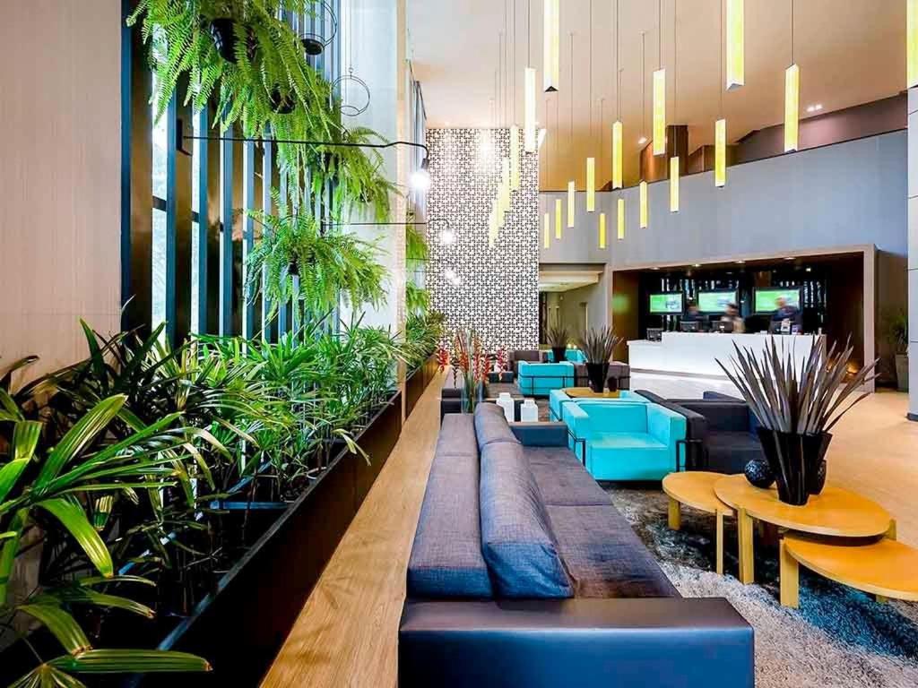 a lobby with blue chairs and potted plants at Apartamento em hotel 5 Estrelas Brasília - GMB0414 in Brasilia