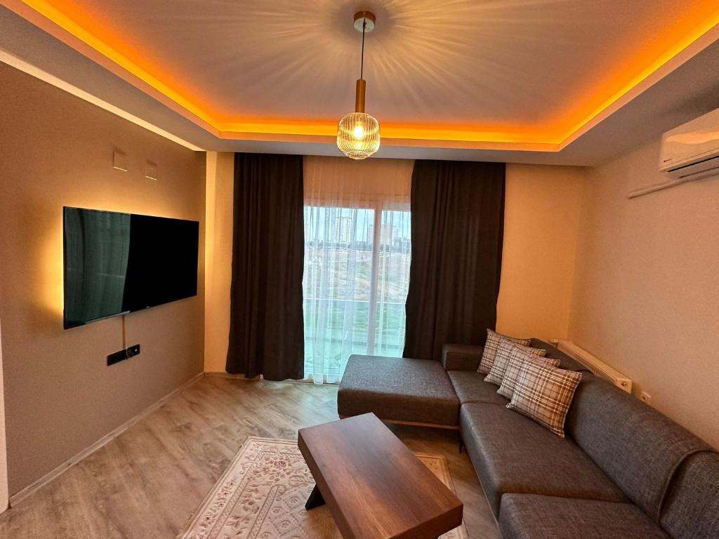 a living room with a couch and a flat screen tv at SAYA LIFE KONAKLAMA in Mersin