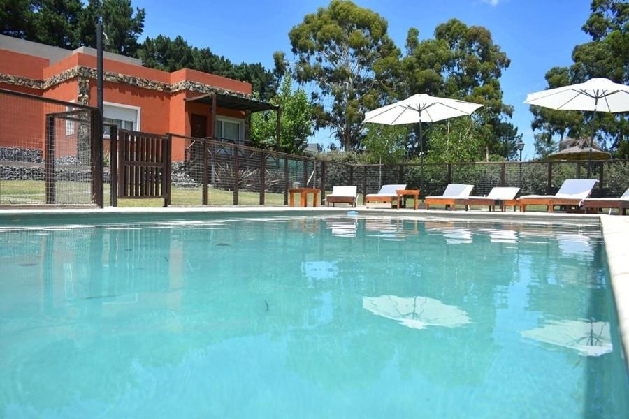 una gran piscina con sillas y sombrillas en Icalma De La Sierra en Tandil