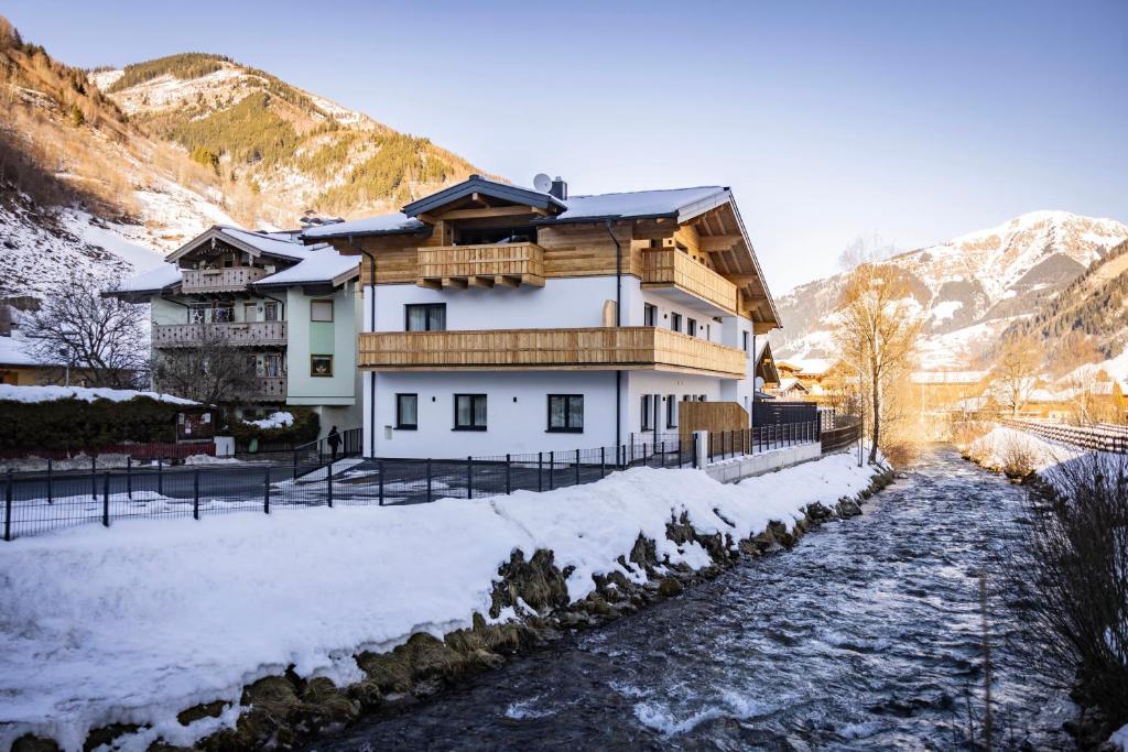 a house in the snow next to a river at RIVERSIDE RAURIS APARTMENTS in Rauris