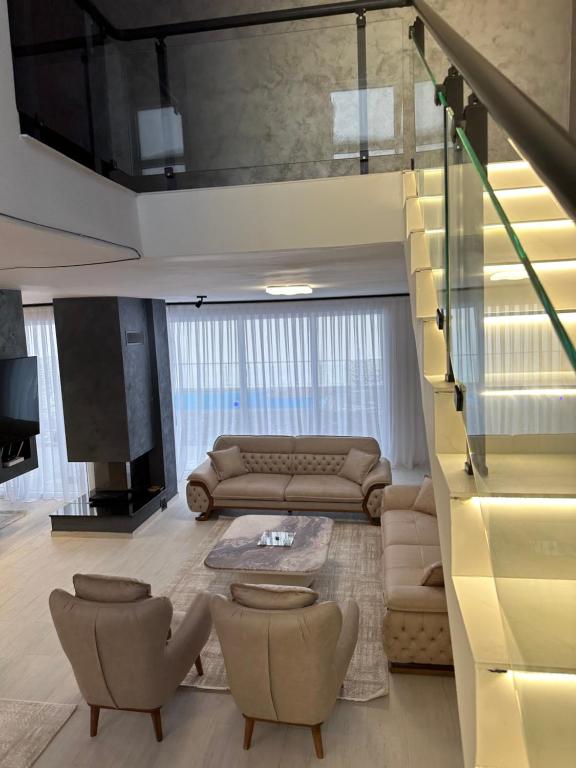 a living room with a couch and chairs and a staircase at Luxury Villa’s in Orllan