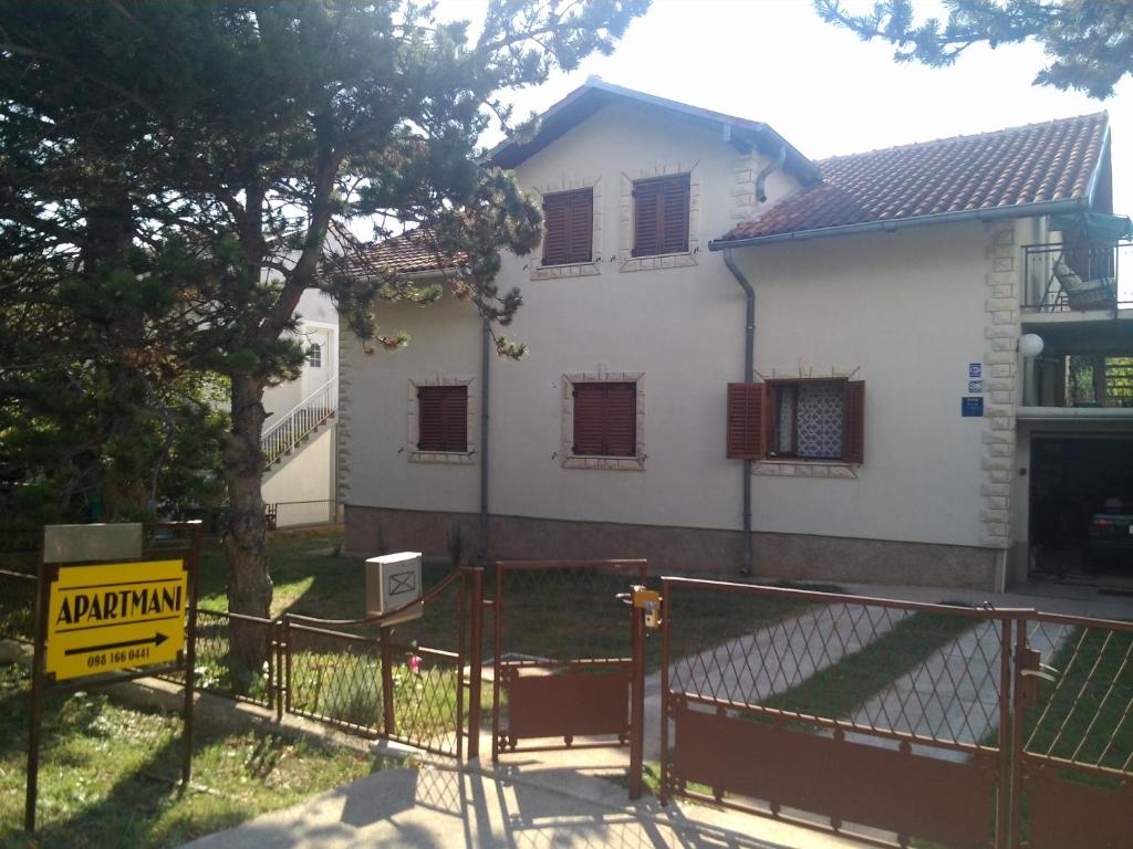 a white house with a gate in front of it at Apartman Amalija in Gornji Karin
