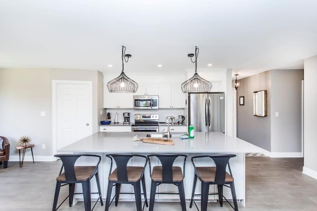 a kitchen with a large white island with chairs at Our Special “Boutique” Quality Home in Old Towne in Niagara-on-the-Lake