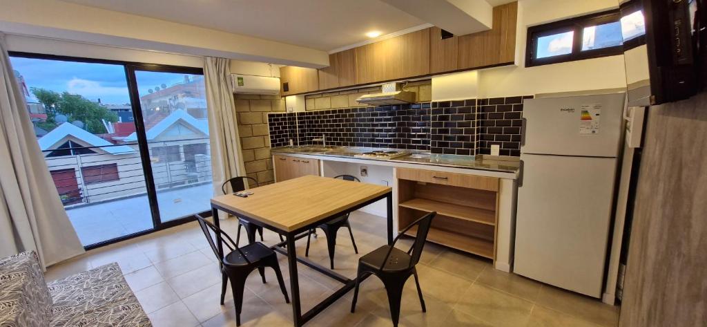 a small kitchen with a table and a refrigerator at Piso 3 frente al lago, centro Villa Carlos Paz pileta privada in Villa Carlos Paz