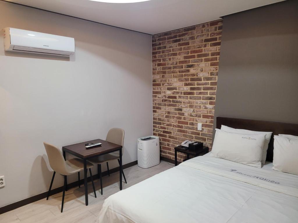 a bedroom with a bed and a table and a brick wall at Romio Motel in Gwangju