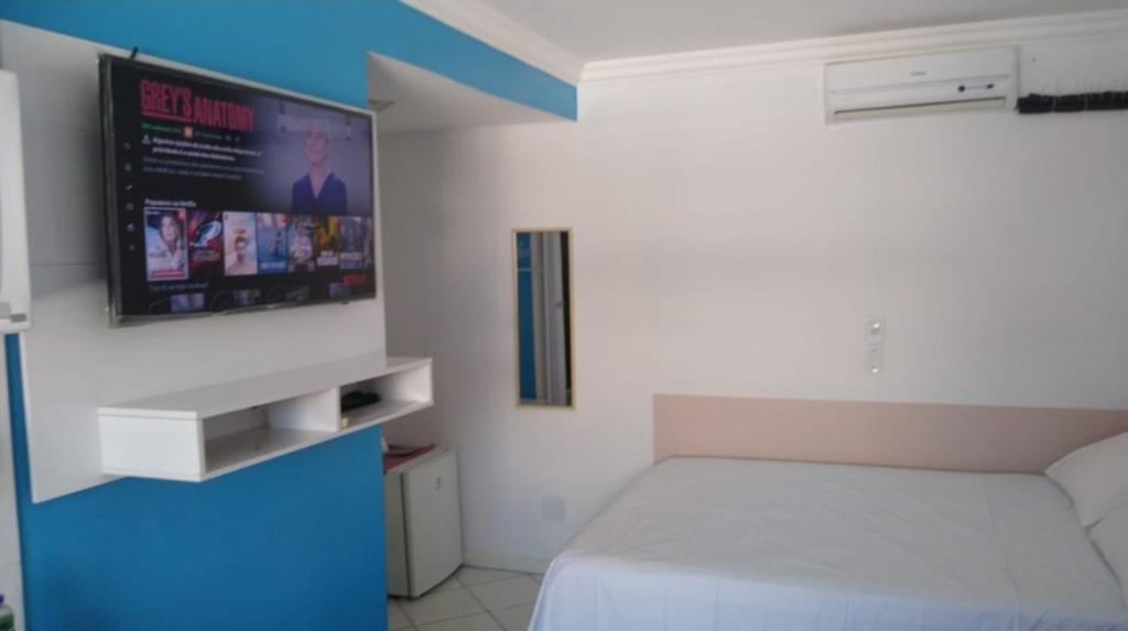 a bedroom with a bed and a tv on the wall at Loft inteiro, aconchegante. in Aracaju
