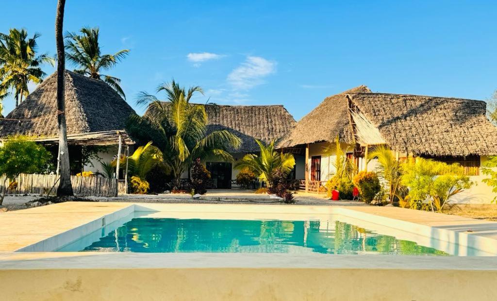 a house with a swimming pool in front of it at Malik Villa Matemwe in Ndizi