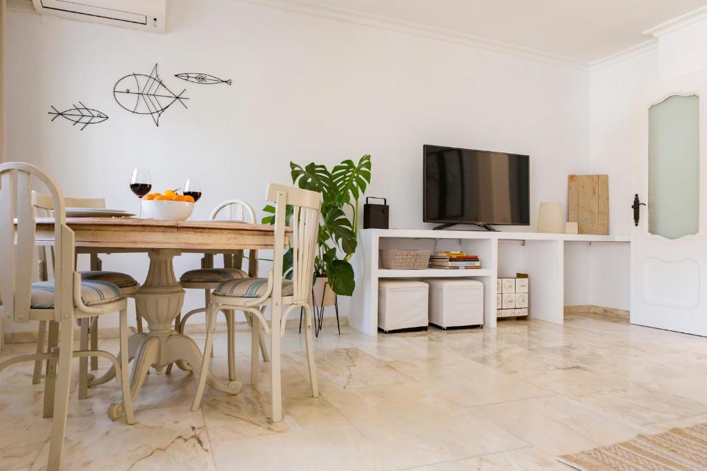 a dining room with a table and a tv at Casa Jardín - residential area -free parking outdoor- Málaga Este in Málaga