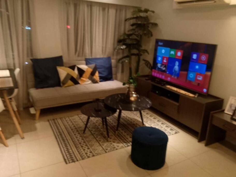 a living room with a couch and a tv at A2J Luxury 2BR BGC Suite Near High Street, Malls in Manila