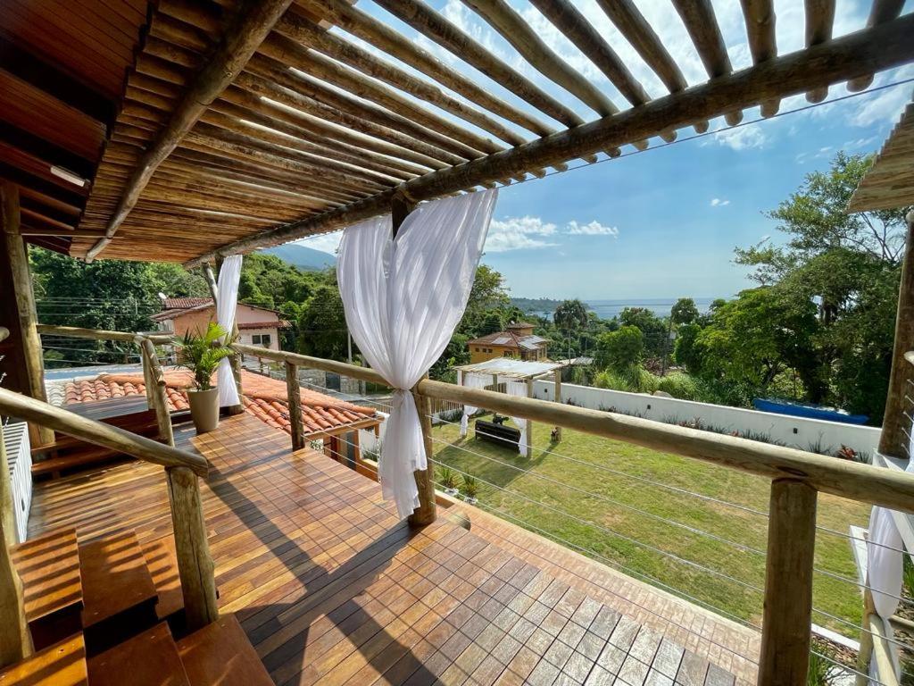 een terras met een pergola en uitzicht op een tuin bij Santomar Guest House in Ilhabela