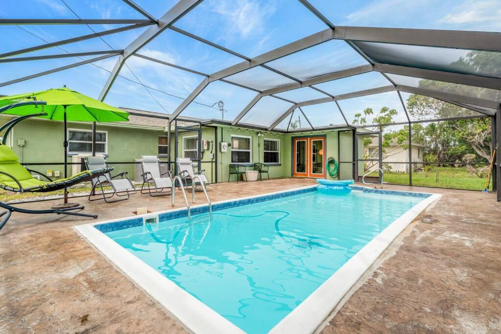 a swimming pool with an umbrella and a house at Groovy Getaway! Heated pool! Something different in Cape Coral