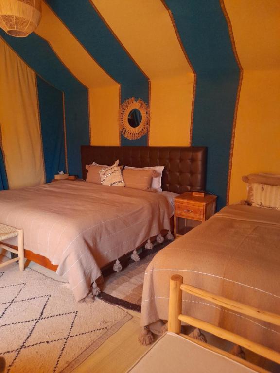 two beds in a room with blue and yellow walls at Merzouga Highdune Camp With Heated Tents in Merzouga
