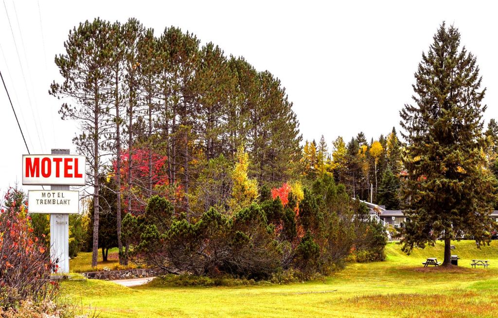 una señal de motel frente a un patio con árboles en Motel Tremblant en Mont-Tremblant