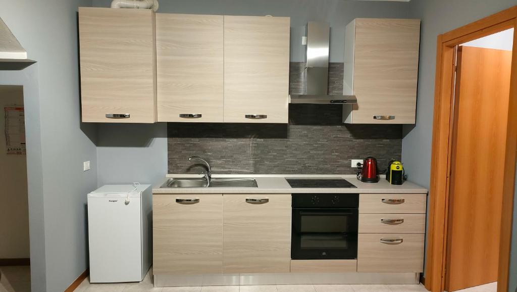 a kitchen with wooden cabinets and a white refrigerator at House IL CORALLO in Castrezatto