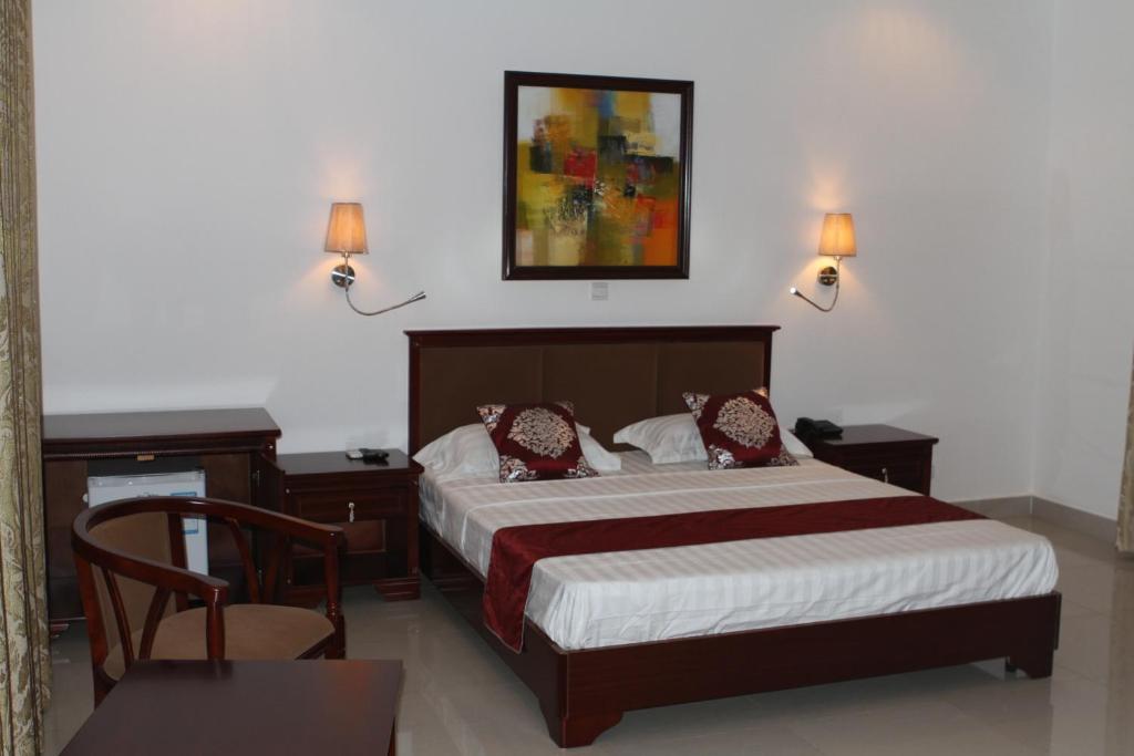 a bedroom with a bed and two lamps and a table at Hotel Residence Flamani in Lomé