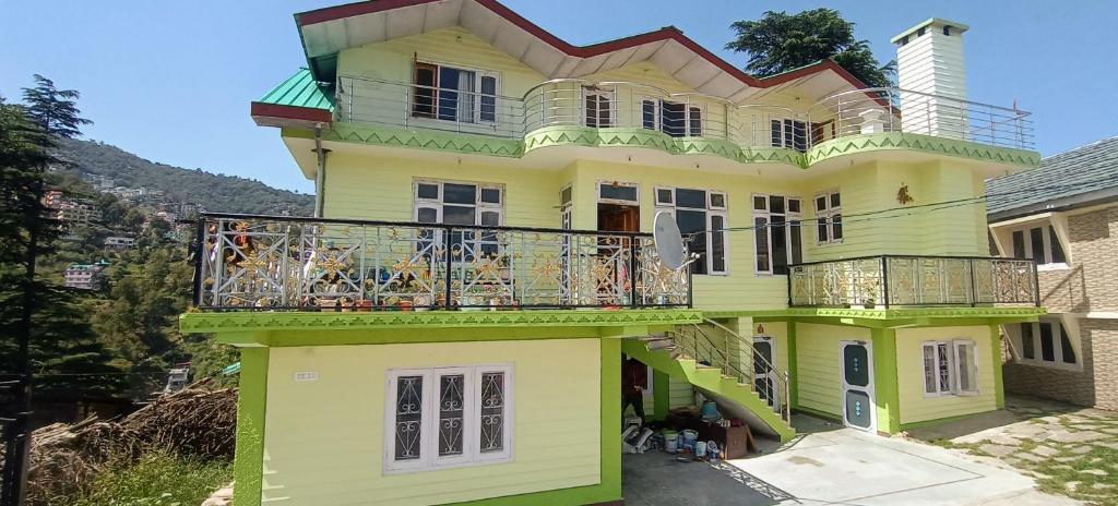 Una casa amarilla con balcón en la parte superior. en Akash Homestay en Shimla