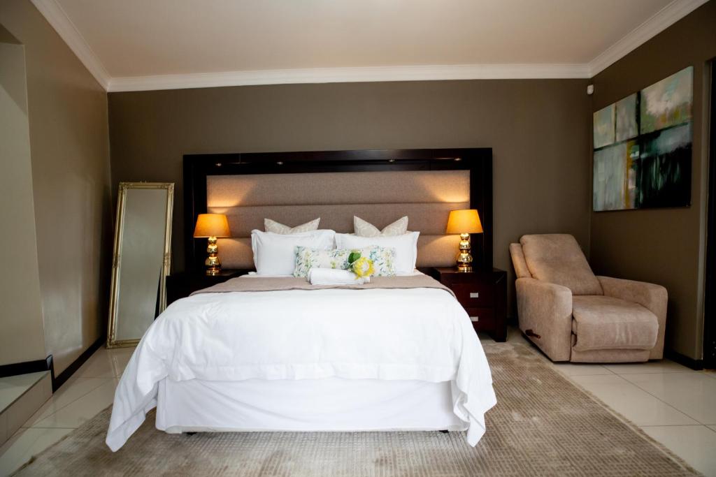 a bedroom with a large white bed and a chair at URlyfstyle 5 bedrooms 10km from OR Tambo Int Airport in Kempton Park