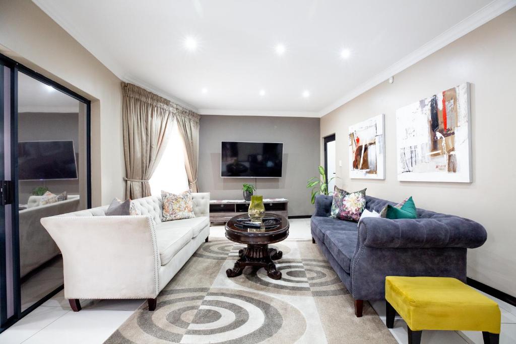 ein Wohnzimmer mit 2 Sofas und einem Tisch in der Unterkunft URlyfstyle 5 bedrooms near OR Tambo international Airport in Kempton Park