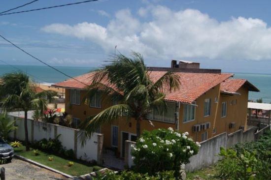 une maison jaune avec un palmier à côté de l'océan dans l'établissement Hotel I 7, à Parnamirim