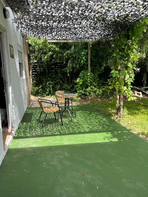 eine Terrasse mit einem Tisch und einem Stuhl auf einer grünen Etage in der Unterkunft Casita sencilla en la Aguada in La Aguada