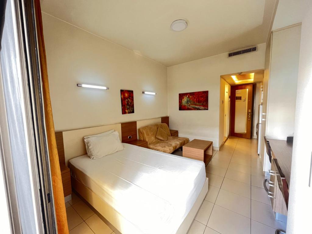 um quarto com uma cama branca e um sofá em Kevens Single Room with Gym and Bar em Jounieh