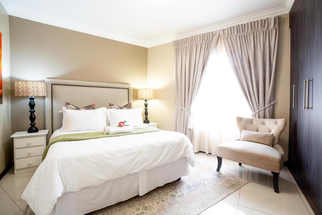 a bedroom with a large bed and a chair at URlyfstyle 5 bedrooms 10km from OR Tambo Int Airport in Kempton Park