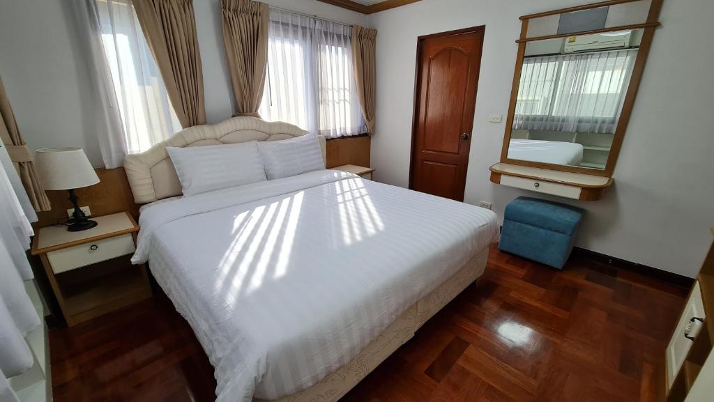 a bedroom with a large white bed and a mirror at Baan Arthit Thong Lo Ekkamai Prompong in Khlong Toei