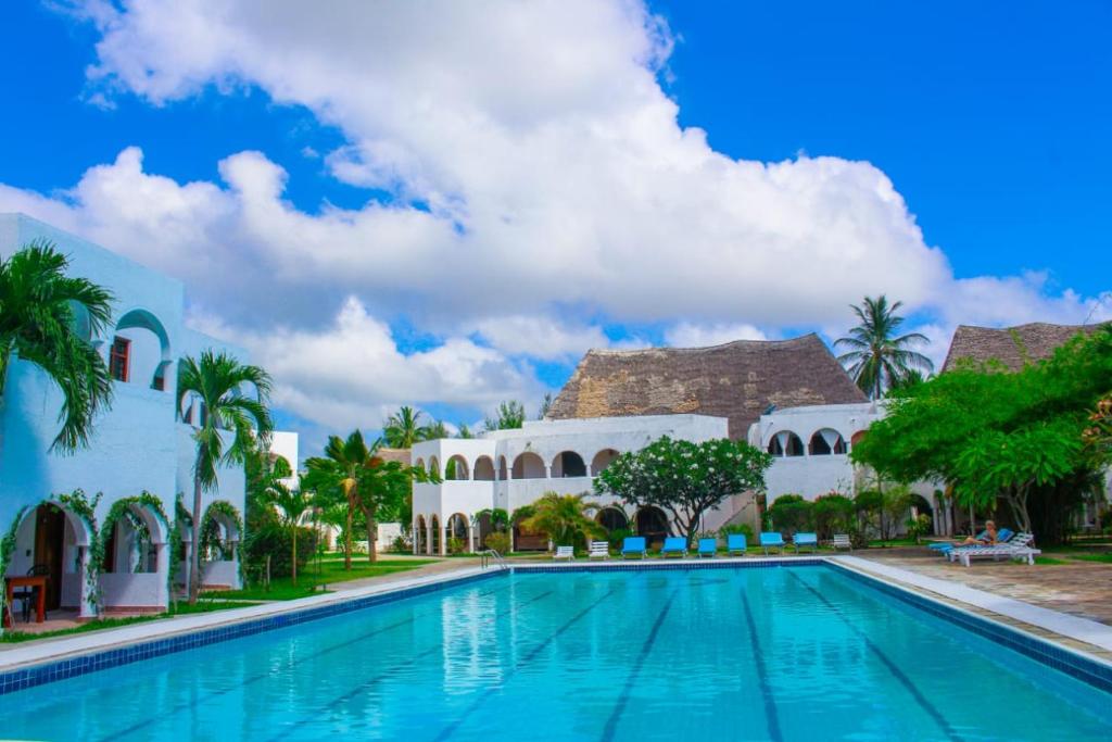 a swimming pool in front of a building at Kaleb's Beachfront Serviced Studio Apartments in Malindi