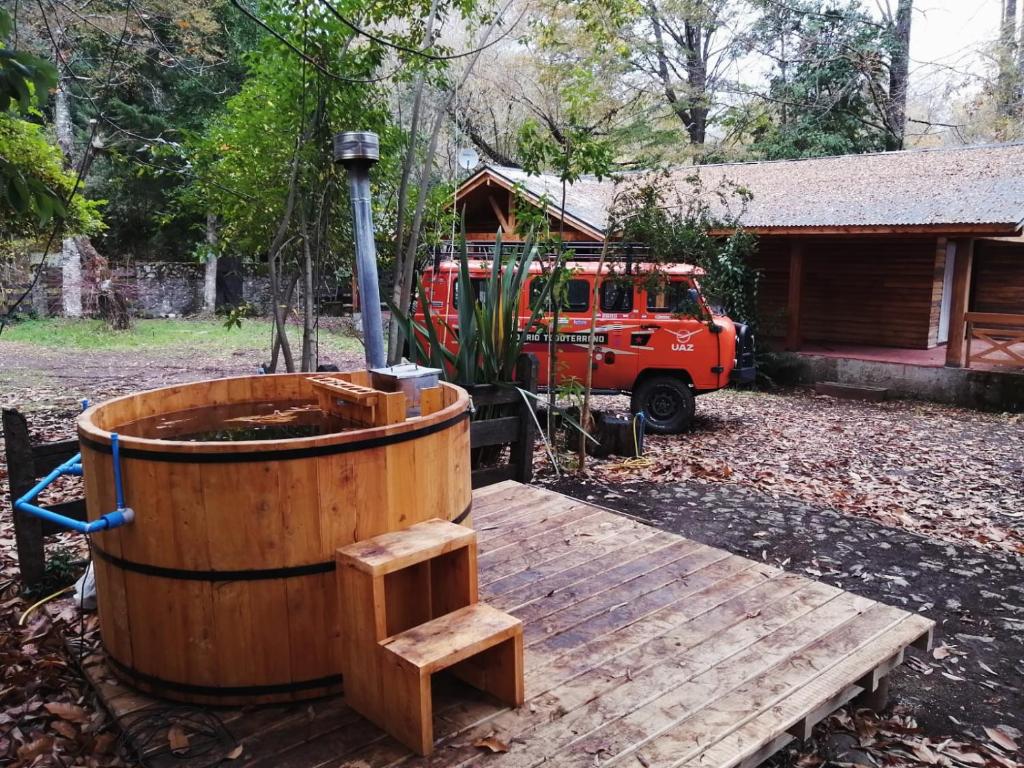 una terraza de madera con bañera de hidromasaje y un camión de bomberos en Casa para 9 personas a 30 metros del lago Caburgua !, en Caburgua