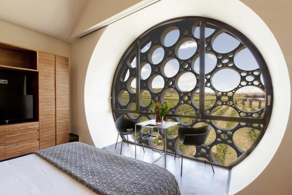 Habitación con ventana grande con mesa y sillas. en Mastinell Cava & Boutique Hotel by Olivia Hotels Collection, en Vilafranca del Penedès