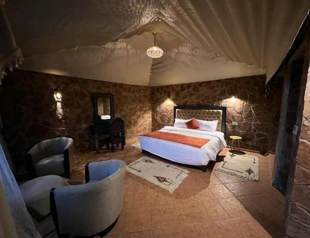 ein Schlafzimmer mit einem Bett und Stühlen in einem Zimmer in der Unterkunft كعب غزال in Merzouga