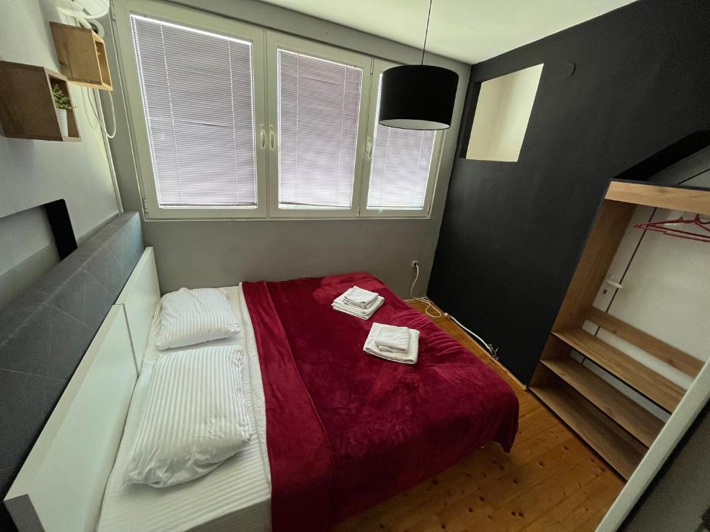 スコピエにあるOld Town M - Rooms & Apartmentsの赤い毛布付きのベッドが備わる小さな客室です。