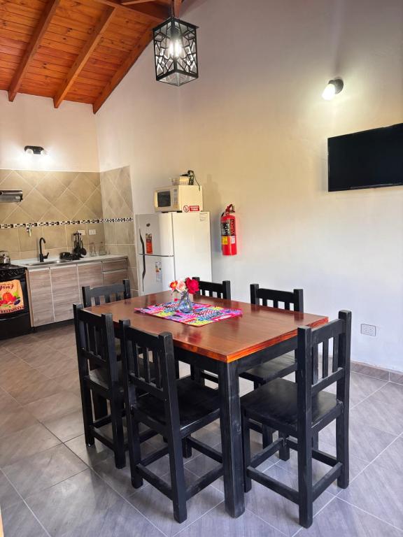 a dining room table with chairs and a refrigerator at Departamentos Merlina in El Hoyo