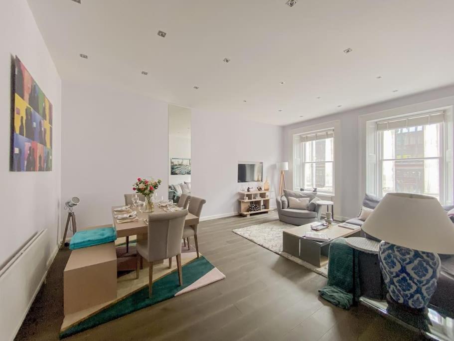 a living room with a table and a dining room at Exceptional apartment in the most desirable street in London