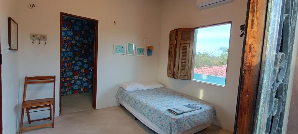 um pequeno quarto com uma cama e uma janela em Casa Tudo Azul em Amontada