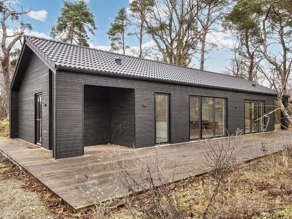 een zwart huis met een houten terras bij Holiday home Knebel LXII in Knebel