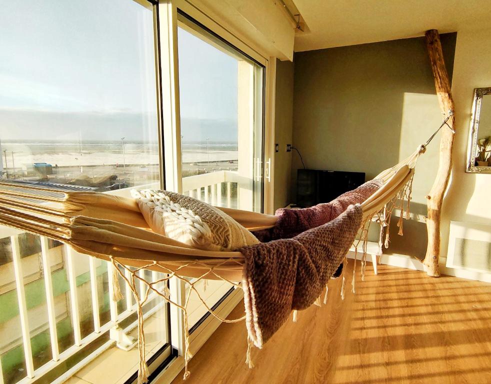 a hammock in a room with a large window at Hamac chic vue mer. in Berck-sur-Mer
