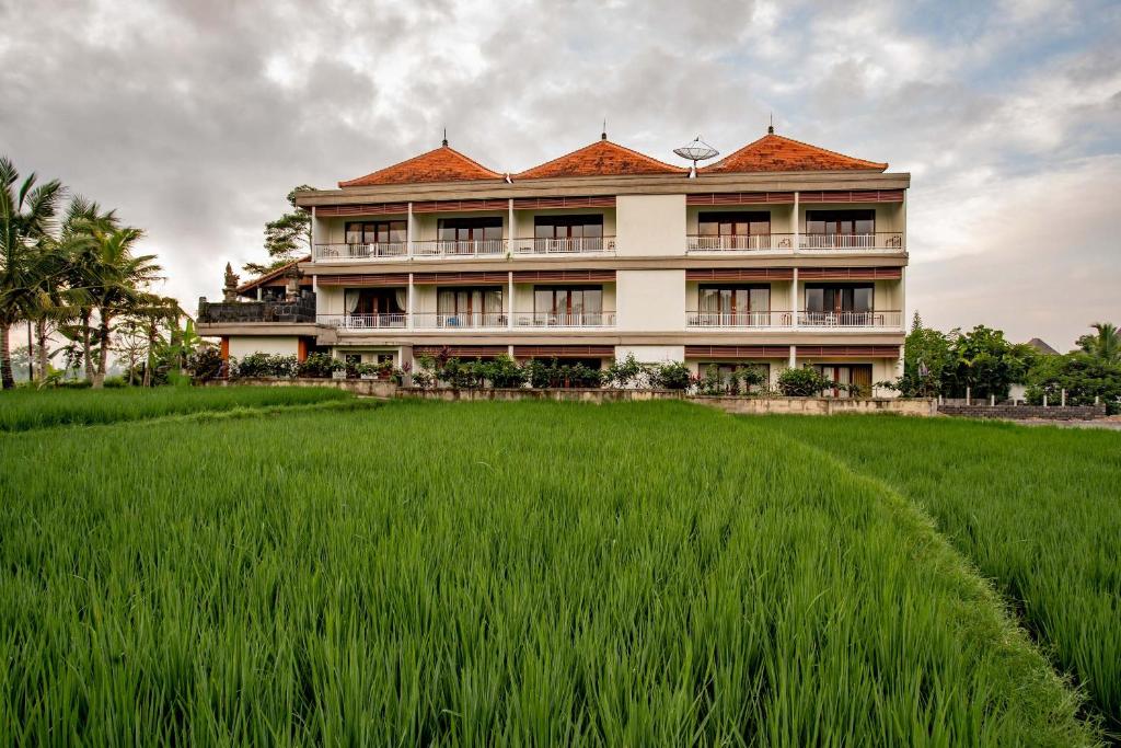 a large building with a field of green grass at Paon Desa Ubud in Ubud