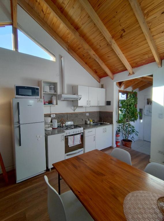 - une cuisine avec des appareils blancs et une table en bois dans l'établissement Playa Serena, à San Carlos de Bariloche