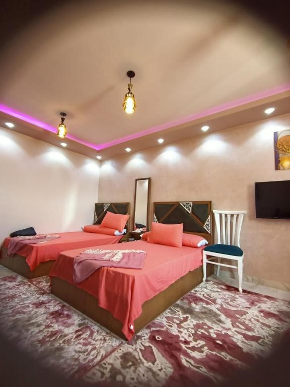 A 5-star hotel room in front of Mansoura University في المنصورة: غرفة نوم بسرير احمر كبير وكرسي