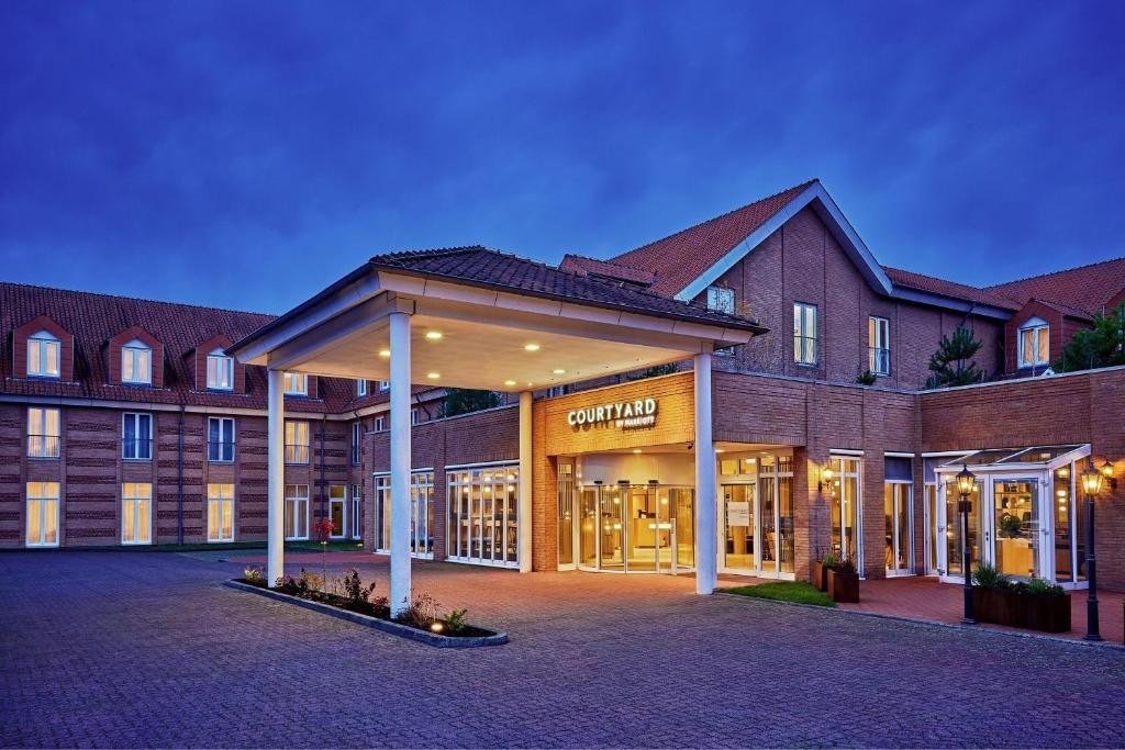 un grand bâtiment en briques avec une cour en face dans l'établissement Courtyard by Marriott Schwerin, à Schwerin