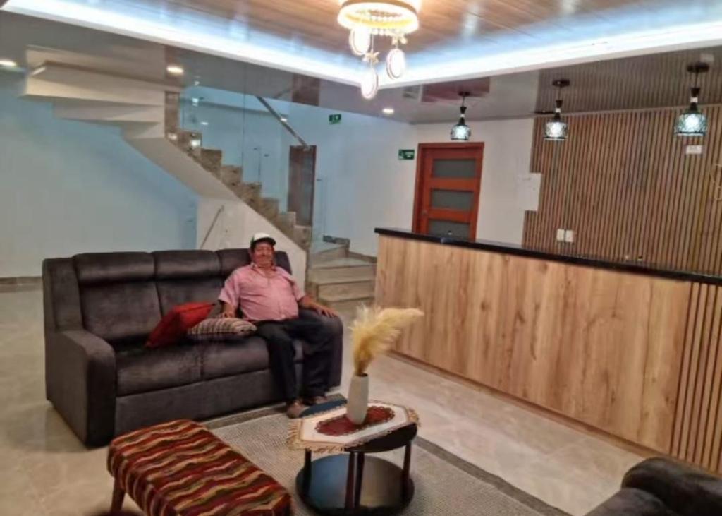 a man sitting on a couch in a living room at Hotel Plaza Real Oiba in Oiba