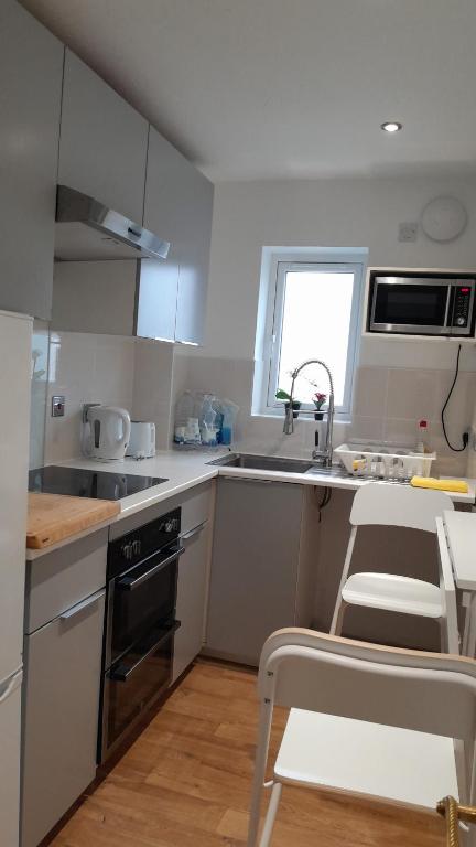 a kitchen with white cabinets and a sink and a stove at Peaceful and cosy apartment in Dorney