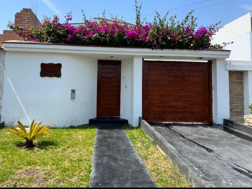 una casa con dos puertas de garaje y flores en el techo en Habitación cerca a los Pantanos de Villa, en Lima