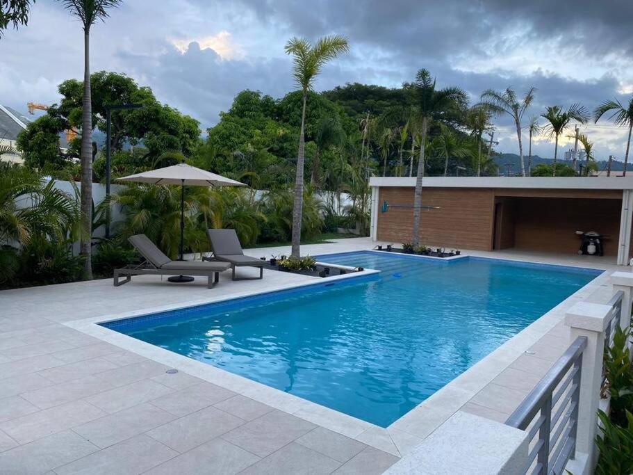 a swimming pool with two chairs and an umbrella at The Echelon Suite in Kingston