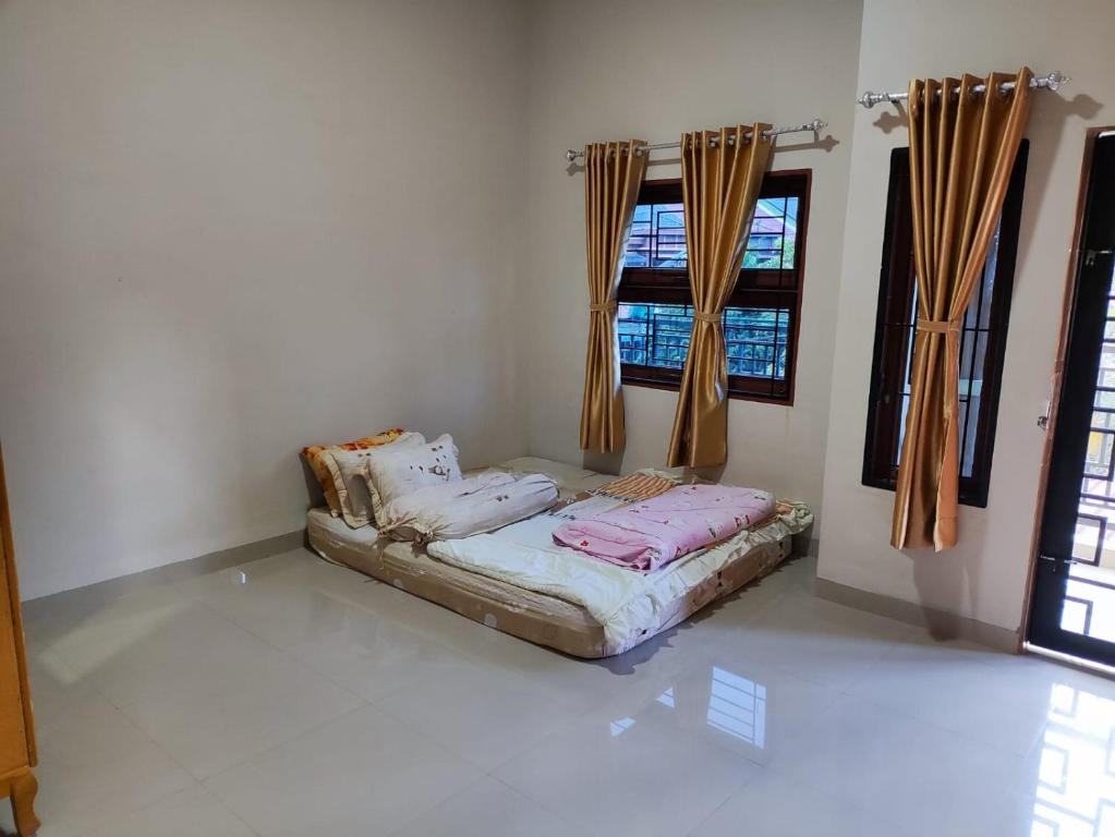 a bed in a room with two windows at VILLA BRASTAGI SINABUNG VIEW in Berastagi