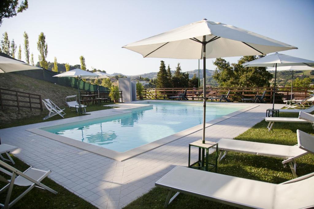 a swimming pool with chairs and umbrellas next to it at Country House Angelo Blù in Urbania