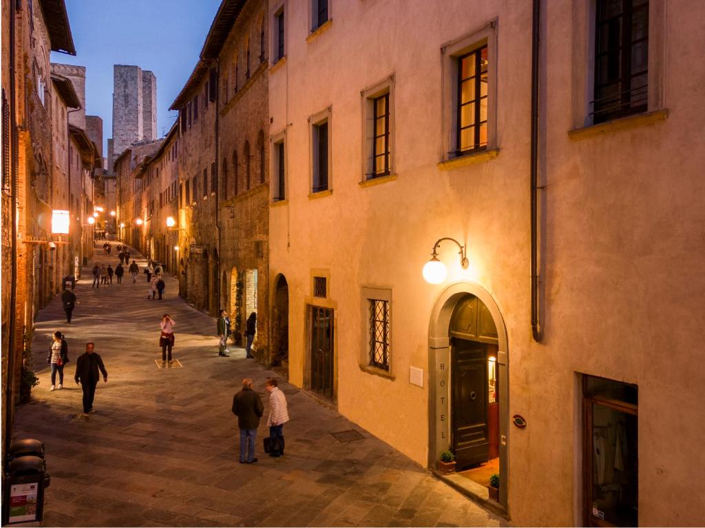 a group of people walking down a street at night at Hotel L'Antico Pozzo in San Gimignano