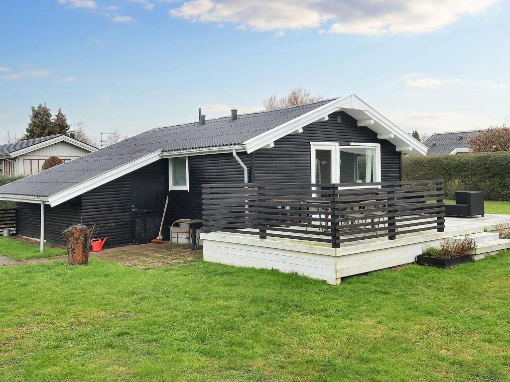 ein schwarzes Haus mit einer Veranda und einem Hof in der Unterkunft Holiday home Karrebæksminde XXXIX in Karrebæksminde