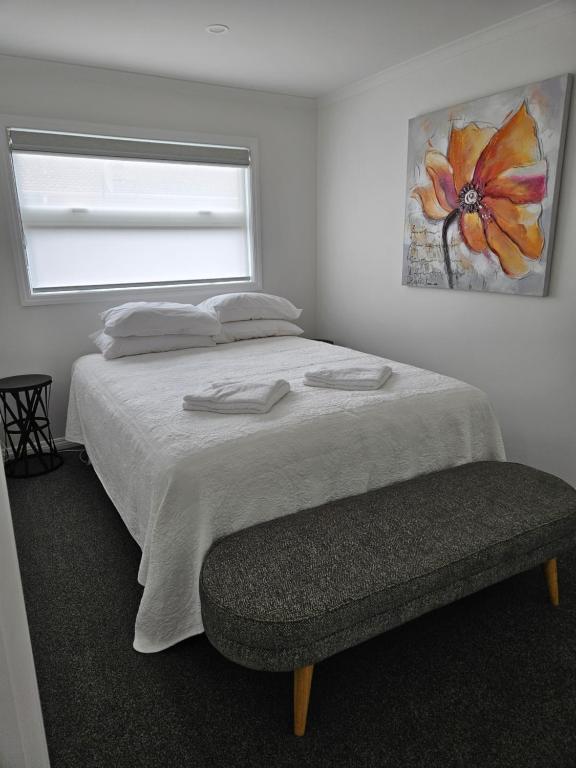 a bedroom with a bed and a window and a bench at Redwood Apartments in Rotorua